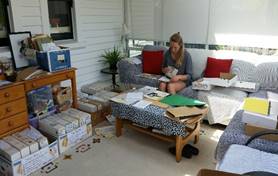 A person sitting on a couch in a room with boxes and a table

Description automatically generated