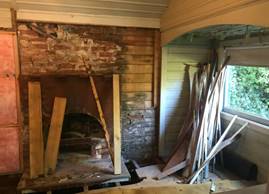 A room with a brick fireplace and wood pieces

Description automatically generated