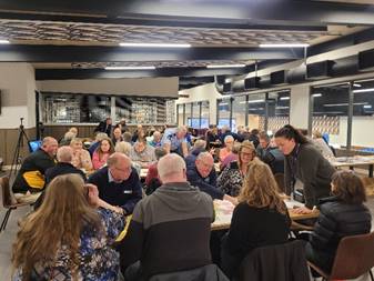 A group of people sitting around tables

Description automatically generated