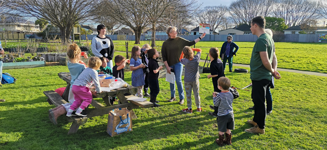 A group of children standing around a picnic table

Description automatically generated