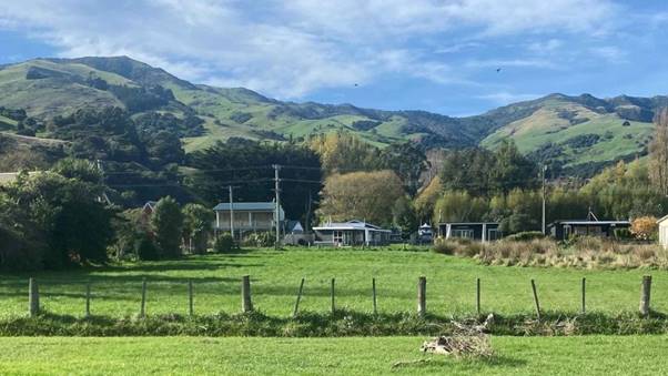 A green field with a fence and a house in the background

Description automatically generated