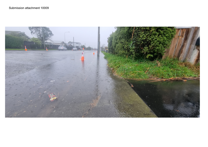 A wet street with a few orange cones on it

Description automatically generated