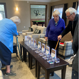 A group of people standing around a table with cards

Description automatically generated