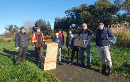 A group of people standing next to a stack of wood boxes

Description automatically generated