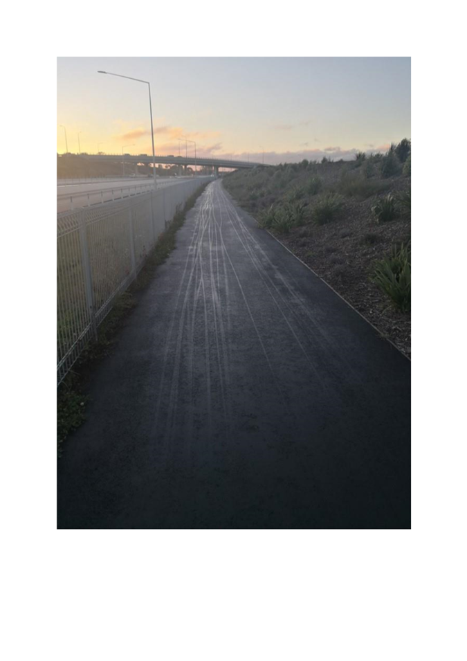 A road with a fence and a bridge

Description automatically generated