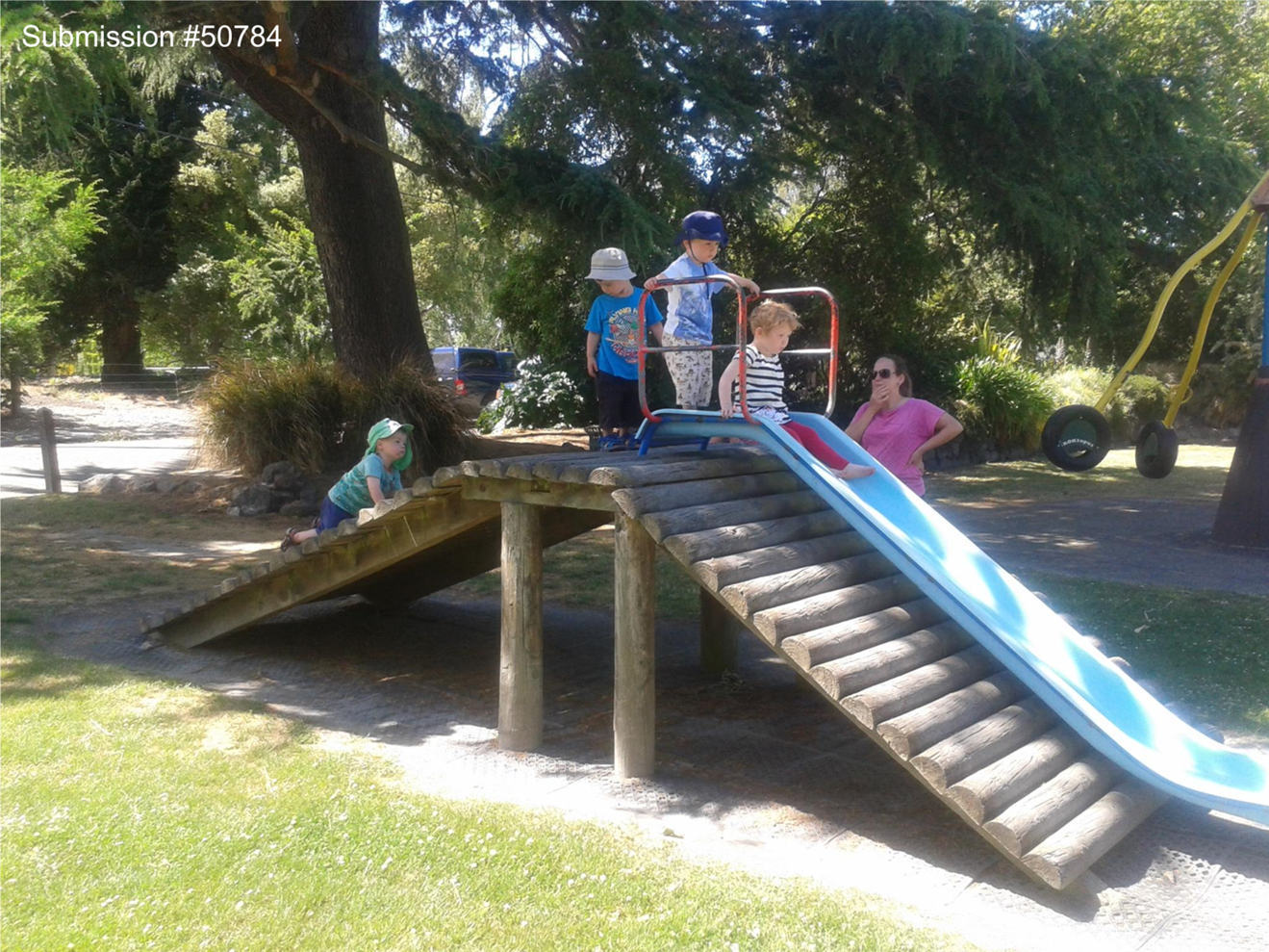 A group of kids playing on a slide

Description automatically generated