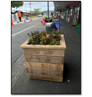 A wooden planter on the street

Description automatically generated