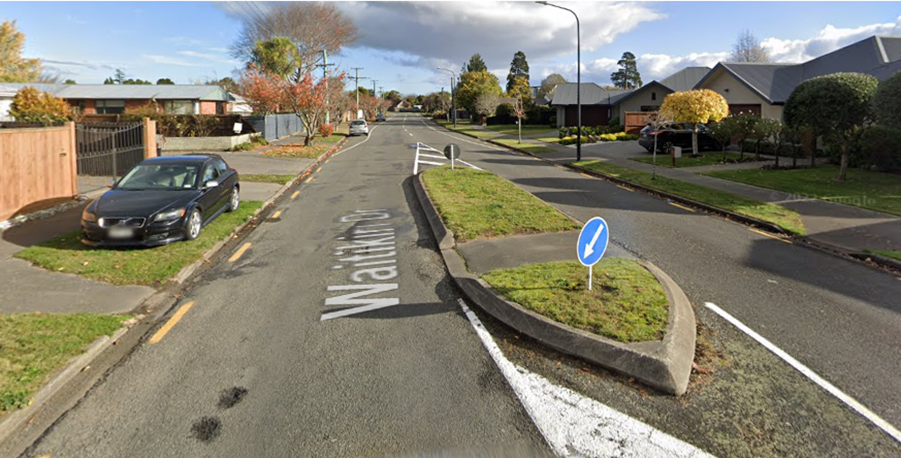 A street with grass and a sign

Description automatically generated