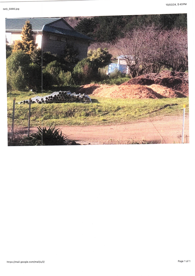 A dirt road with dirt piles and trees

Description automatically generated