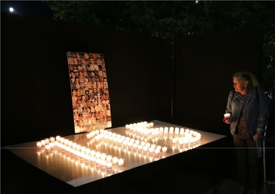 A person standing next to a table with candles

Description automatically generated