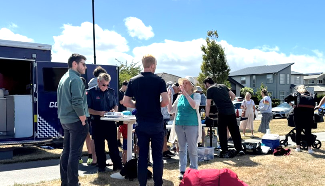 A group of people standing around a table

Description automatically generated