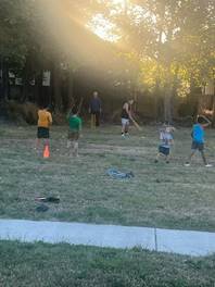 A group of people playing in a field

Description automatically generated
