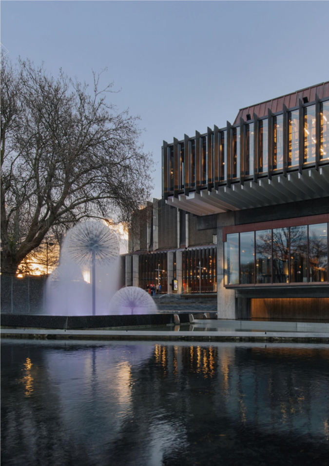 A building with a fountain and a pond

Description automatically generated