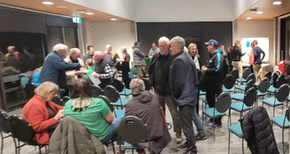 A group of people in a room sitting and standing, having discussions with one another.
