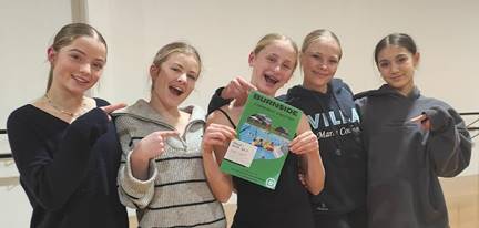 A group of girls holding a book

Description automatically generated