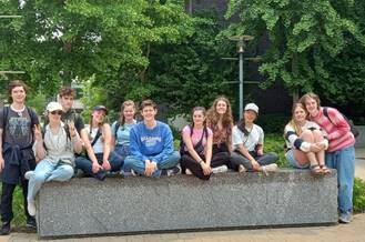 A group of people sitting on a wall

Description automatically generated