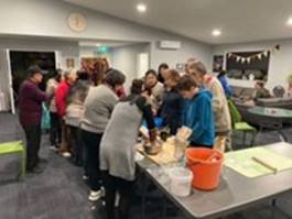 A group of people standing around a table

Description automatically generated