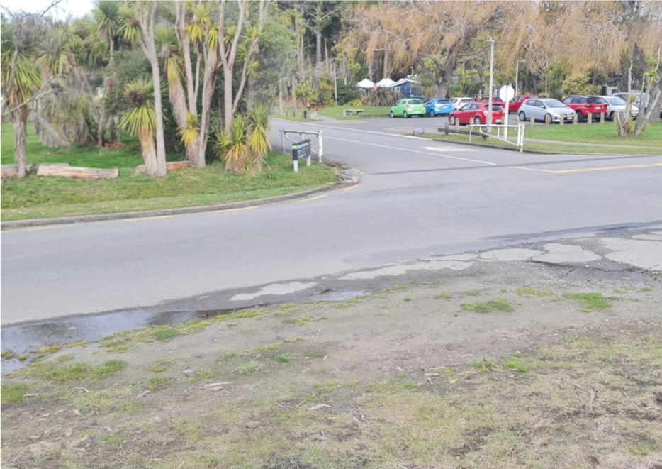 A road with cars parked in the middle

Description automatically generated