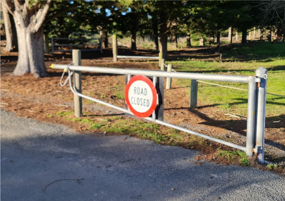A road closed sign on a metal fence

Description automatically generated