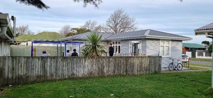 A side view of the Hornby Youth Hangout, a house with a fence and grass
