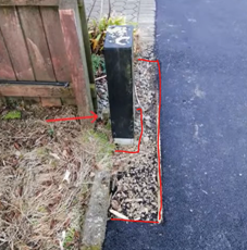 A power box between a fence to the left and a footpath to the right 