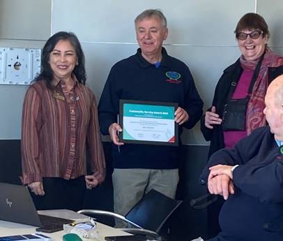 An image of Gary Chisholm holding his certificate, standing in between Board members Marie Pollisco and Helen Broughton. 