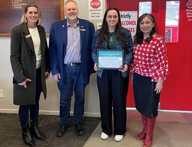 Emily Austin holding their certificate with Board members Sarah Brunton, Marie Pollisco and Mark Peters.