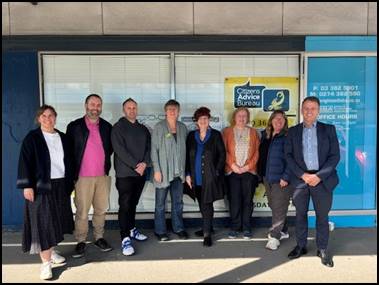 A group of people standing in front of a building

Description automatically generated