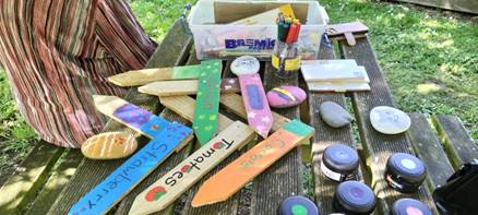 Colourfully painted small wooden vegetable and garden signs and paints on a picnic table.
