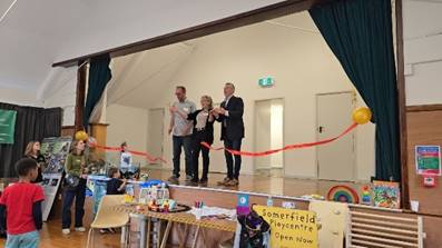 A group of people standing on a stage with a red ribbon

Description automatically generated