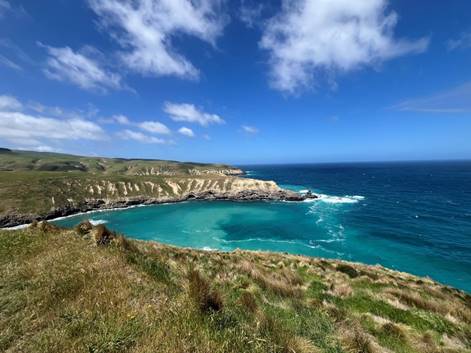 A body of water with a cliff and grass

Description automatically generated