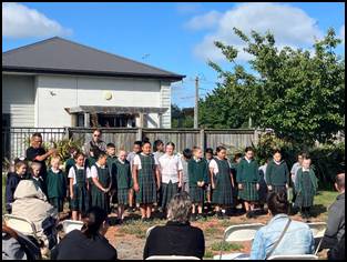 A group of children in green skirts standing in a circle

Description automatically generated