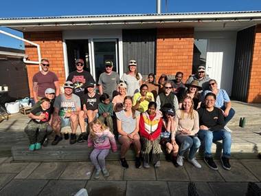 A group of residents seated outside a house, smiling for the camera.