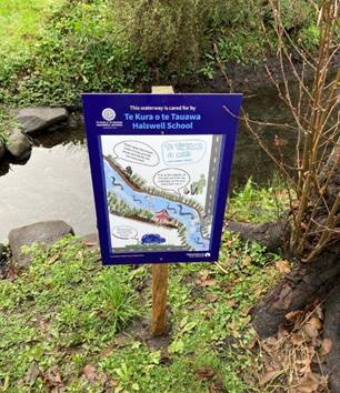 A sign beside a waterway noting that Te Kura o te Tauawa Halswell School cares for the waterway that runs through the Muir Park.