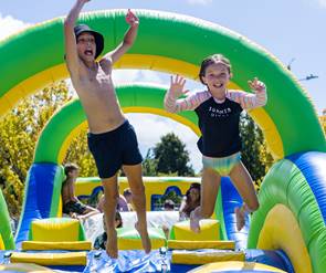 Two children jumping on a inflatable slide
