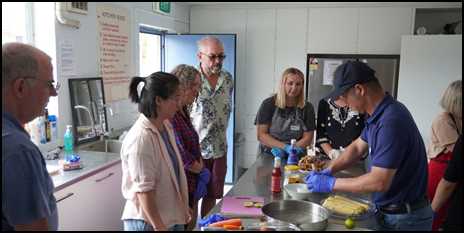 A group of people standing around a table

Description automatically generated