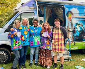 A group of people posing for a photo in front of a van