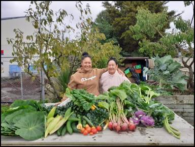 Two women standing next to a table full of vegetables

AI-generated content may be incorrect.