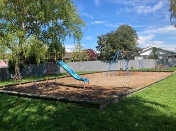 A playground in a yard

Description automatically generated