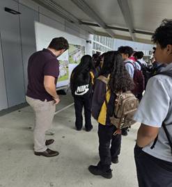 A teacher and a group of students standing around a whiteboard.