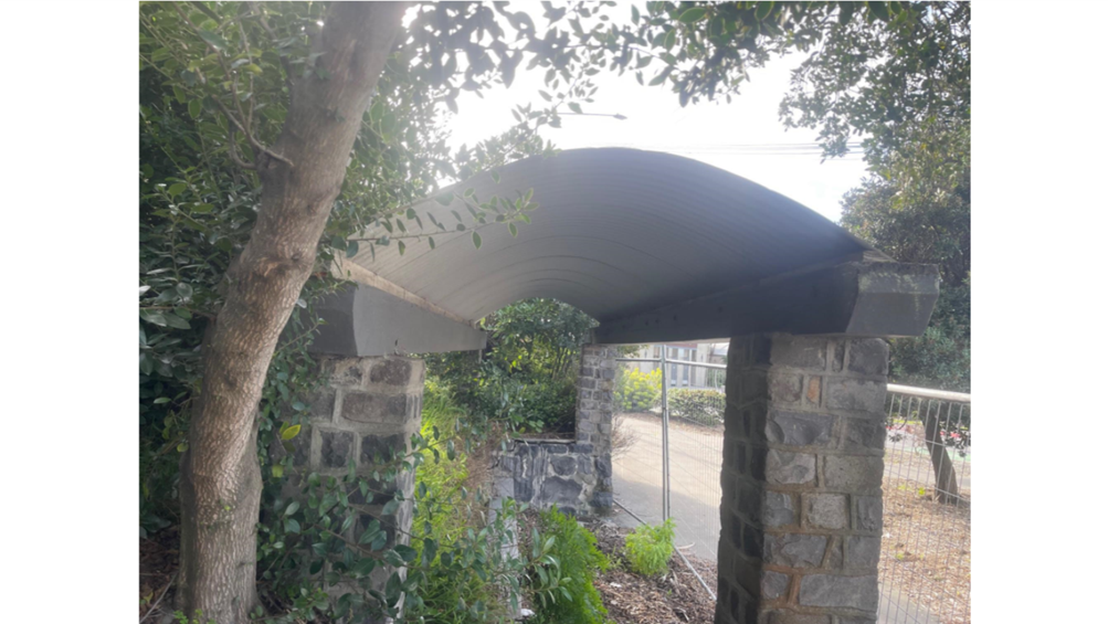 A stone archway with a roof over a stone wall

AI-generated content may be incorrect.