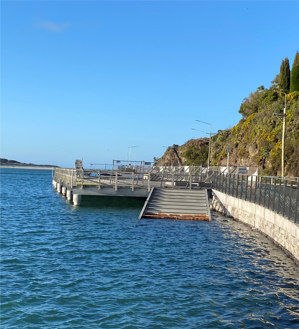 A dock over water with a hill and trees

AI-generated content may be incorrect.
