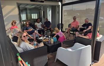Photograph of a Halswell Downs residents gathered on a covered outdoor patio, with snacks and drinks. 