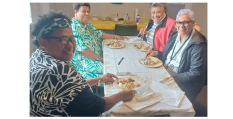 A photograph of four individuals seated at a table enjoying their meal.