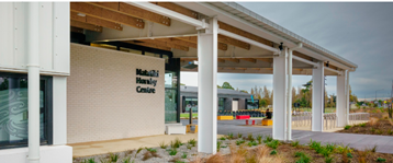 Photograph of Matatiki Hornby Centre with large glass windows, and a covered walkway supported by white pillars. 